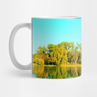 Scene from Lago Cedri in Lapedona with trees bathed in sunlight and the calm waters of the lake reflecting that lushness Mug